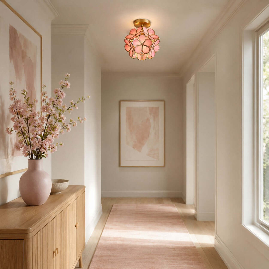 Pink-petal Clérachic ceiling light above a hallway with a wooden sideboard, a pink vase of blossom and a pale runner.