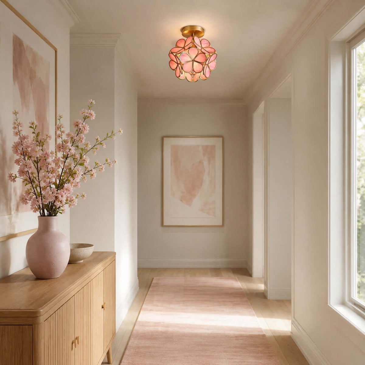 Pink-petal Clérachic ceiling light above a hallway with a wooden sideboard, a pink vase of blossom and a pale runner.
