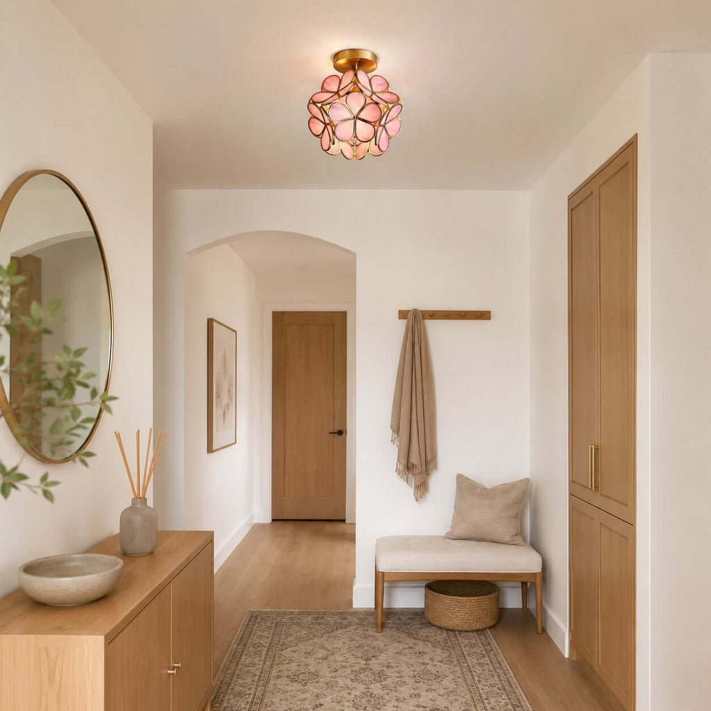 Pink glass-petal Clérachic ceiling light in an entrance with an arched doorway, a round mirror and a cushioned bench.