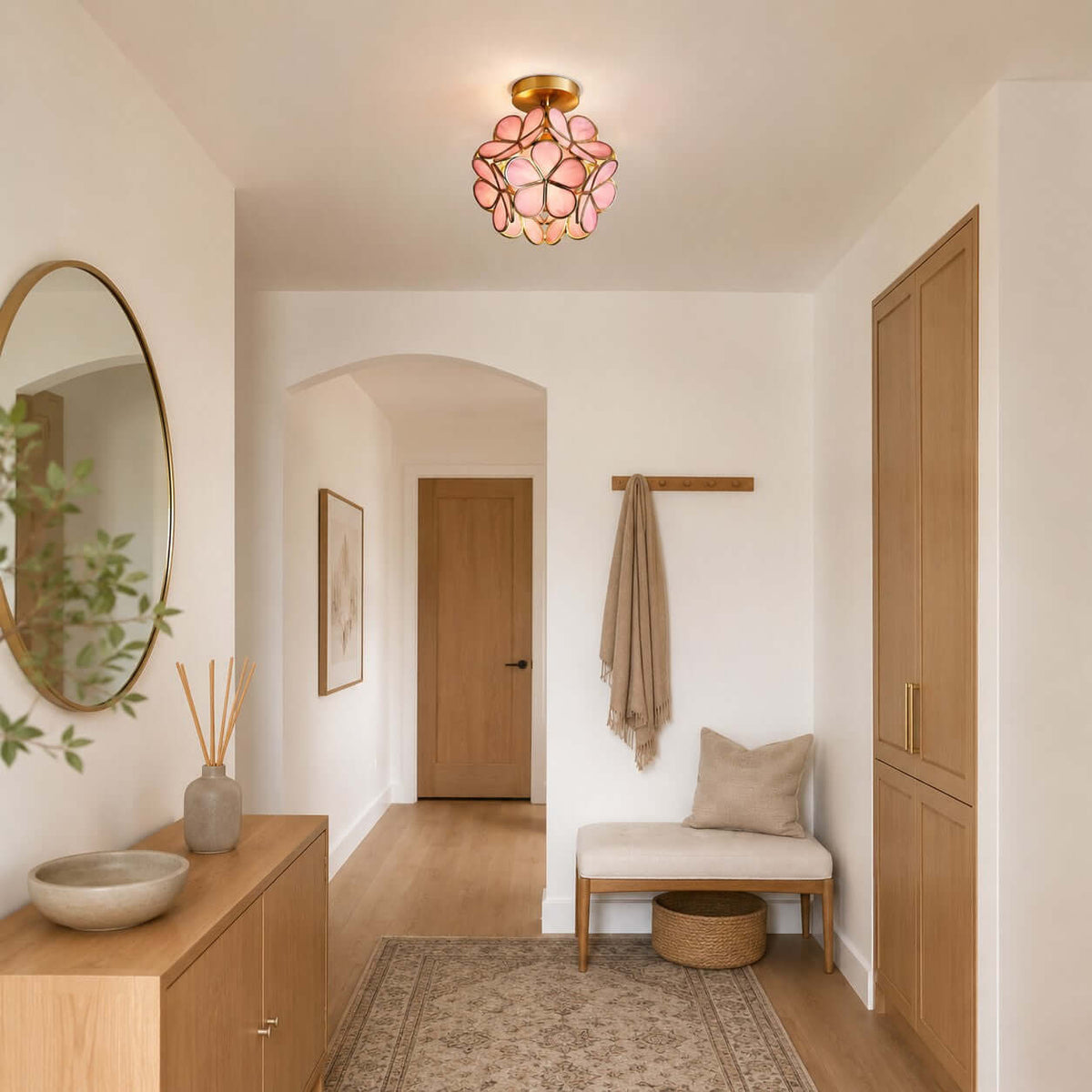 Pink glass-petal Clérachic ceiling light in an entrance with an arched doorway, a round mirror and a cushioned bench.