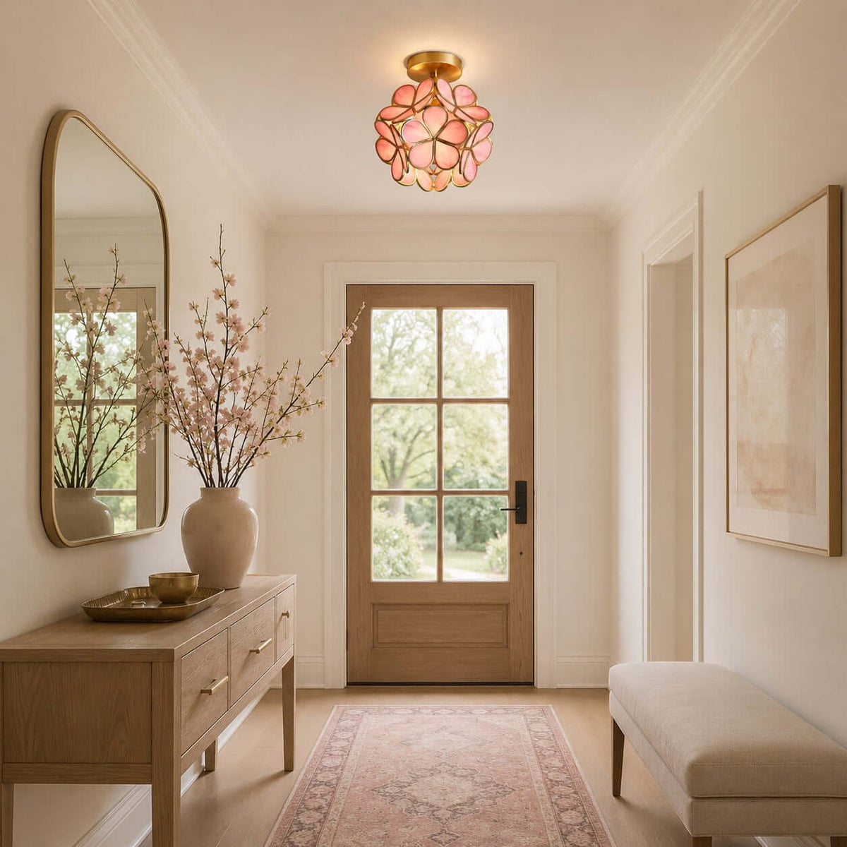 Pink Clérachic ceiling light glowing above a hall console, with a glazed wooden door, an oval mirror and a pink rug.