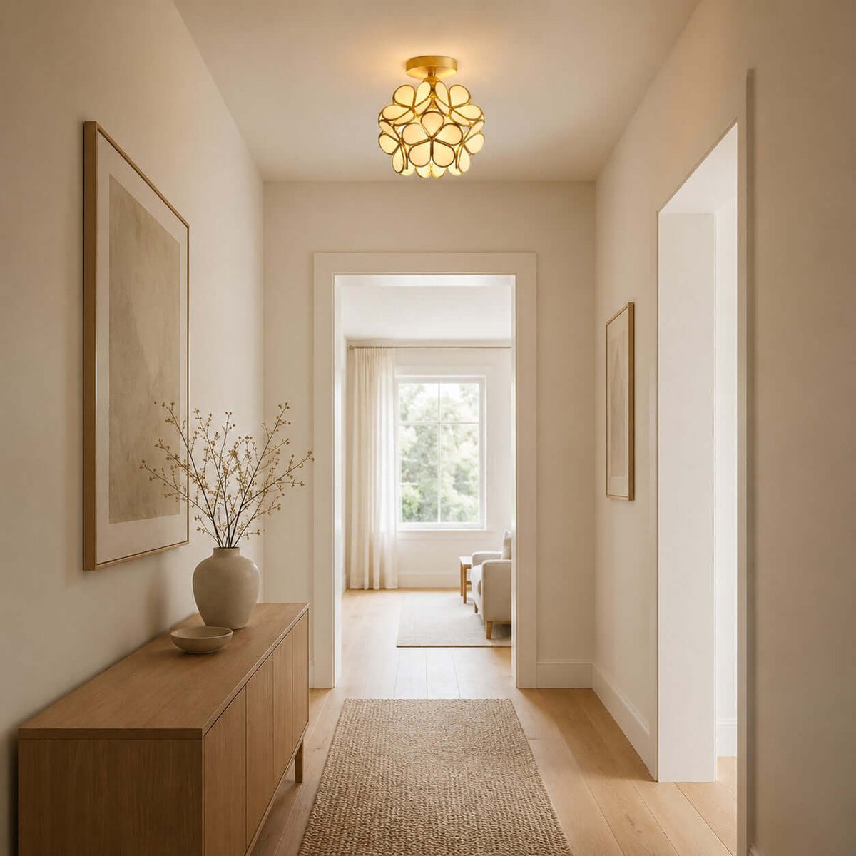 White glass-petal Clérachic ceiling light lit warm in a hallway with a wooden sideboard and a view through to a window.