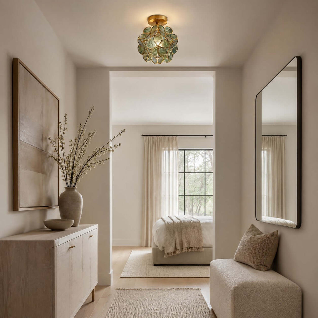 Blue-green glass-petal Clérachic ceiling light above a hallway with a stone console, two mirrors and a bedroom beyond.