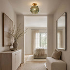 Blue-green glass-petal Clérachic ceiling light above a hallway with a stone console, two mirrors and a bedroom beyond.