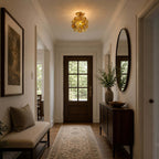 Clear-petal Clérachic ceiling light in a hallway with a dark wood front door, an oval mirror and a patterned runner.