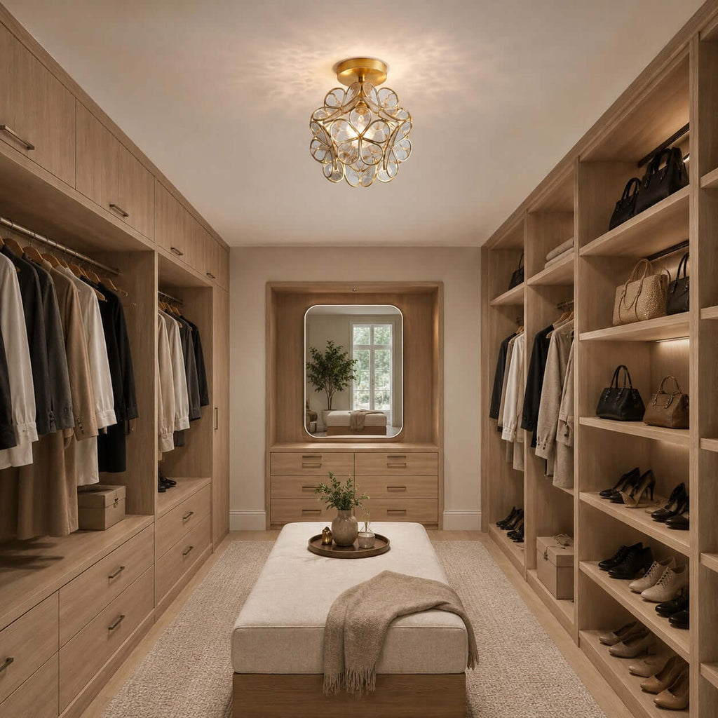 Clear glass-petal Clérachic ceiling light in a walk-in wardrobe with open shelves, hanging clothes and a cushioned ottoman.