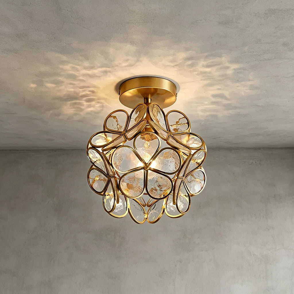 Clear glass-petal Clérachic ceiling light with a few small crystal drops, casting a pattern on a grey plaster ceiling.