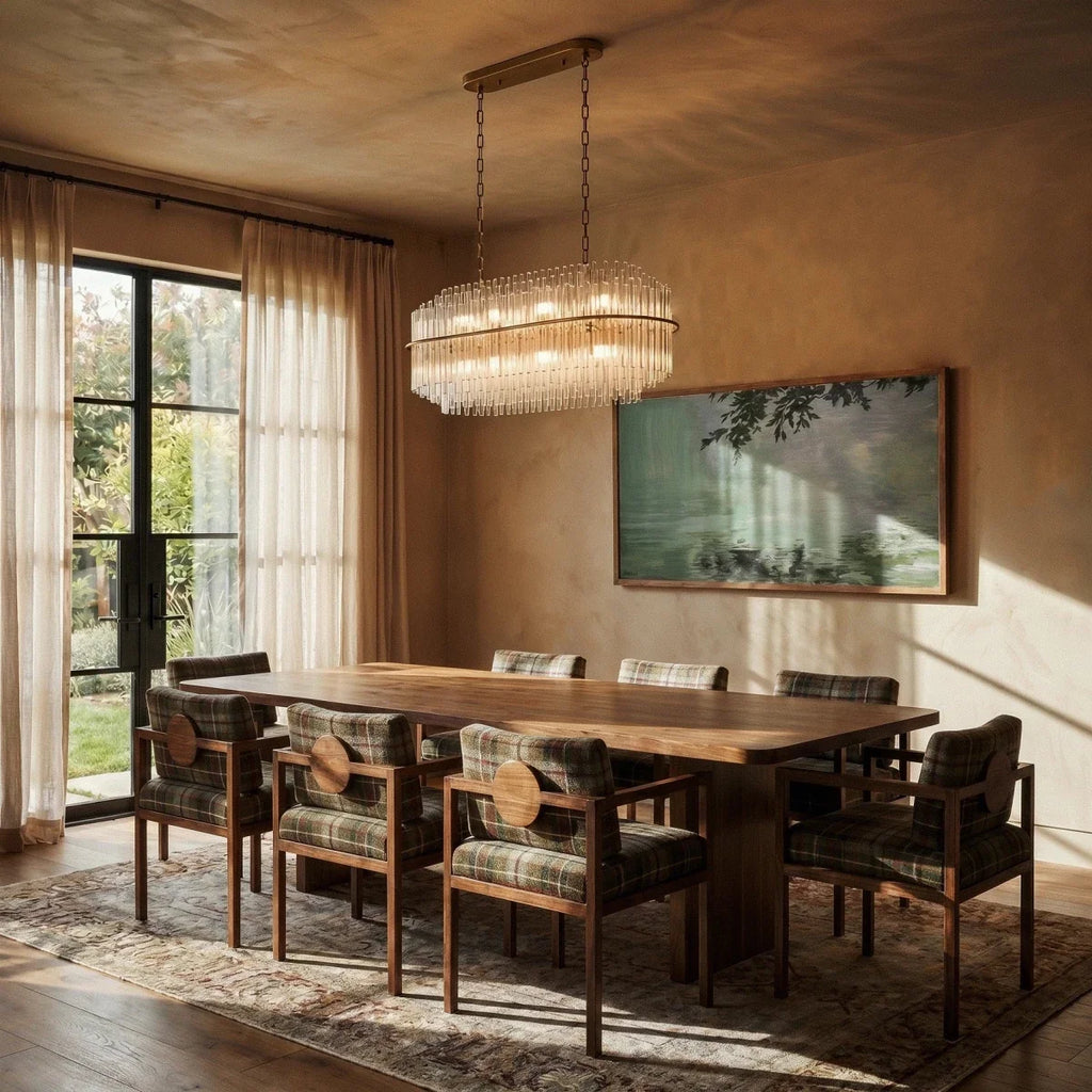 Clérachic long oval glass-rod chandelier glowing above a walnut dining table, with plaid armchairs and sheer curtains.