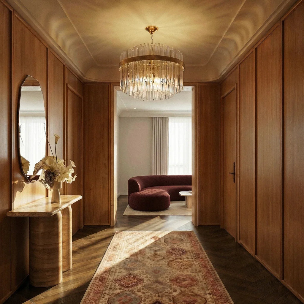 Clérachic round glass-rod chandelier with a gold band, lit in a panelled hallway with a console table and a runner.