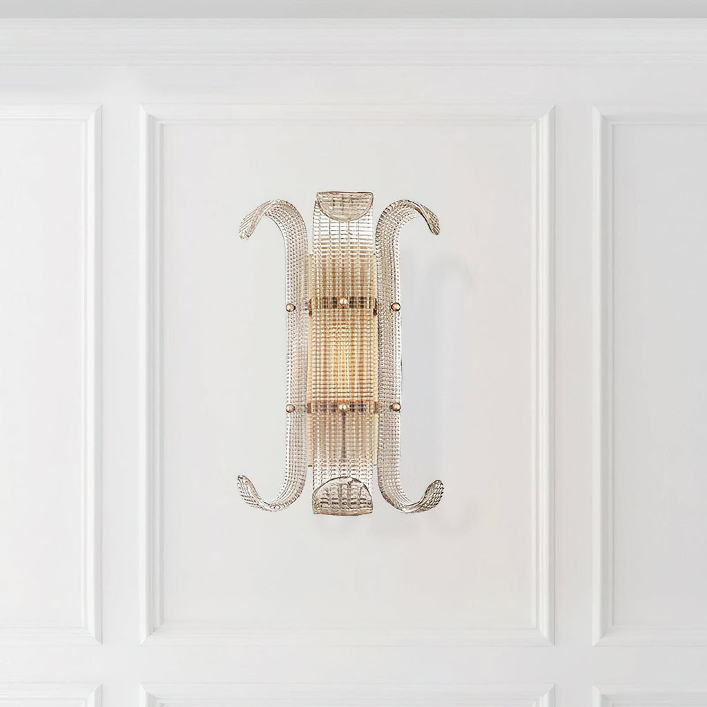 This Clérachic wall light hangs on a white panelled wall, its ribbed glass and curled arms glowing softly in warm light.