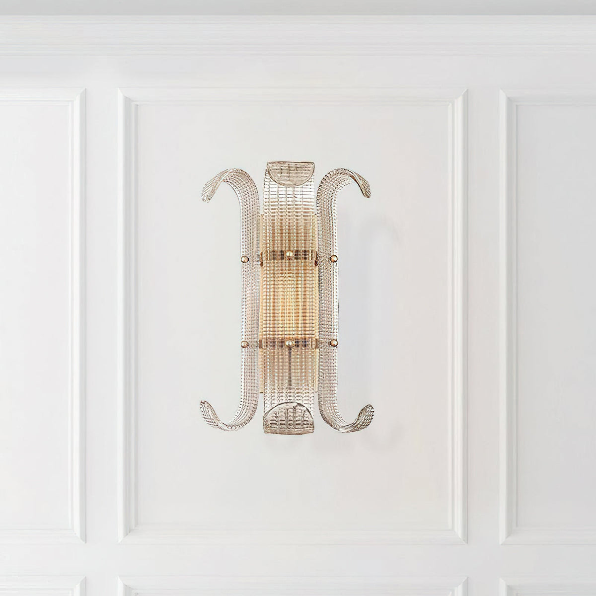 This Clérachic wall light hangs on a white panelled wall, its ribbed glass and curled arms glowing softly in warm light.