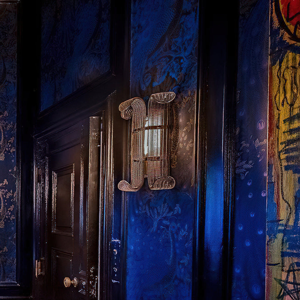 Unlit Clérachic glass-rod wall light mounted on a deep blue wall beside a black door, with colourful graffiti-style art at the edge.