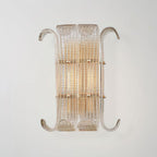 The wider version of this Clérachic wall light, with two glass panels side by side and curled arms, glowing warm on a light grey wall.