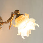 Close-up of the lit Clérachic glass rose wall sconce, where the brass gallery collar grips the layered glass petals above the cherub.