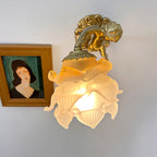 The Clérachic glass rose wall sconce lit beside a framed portrait, its ruffled petals fanning out below the scalloped brass collar.