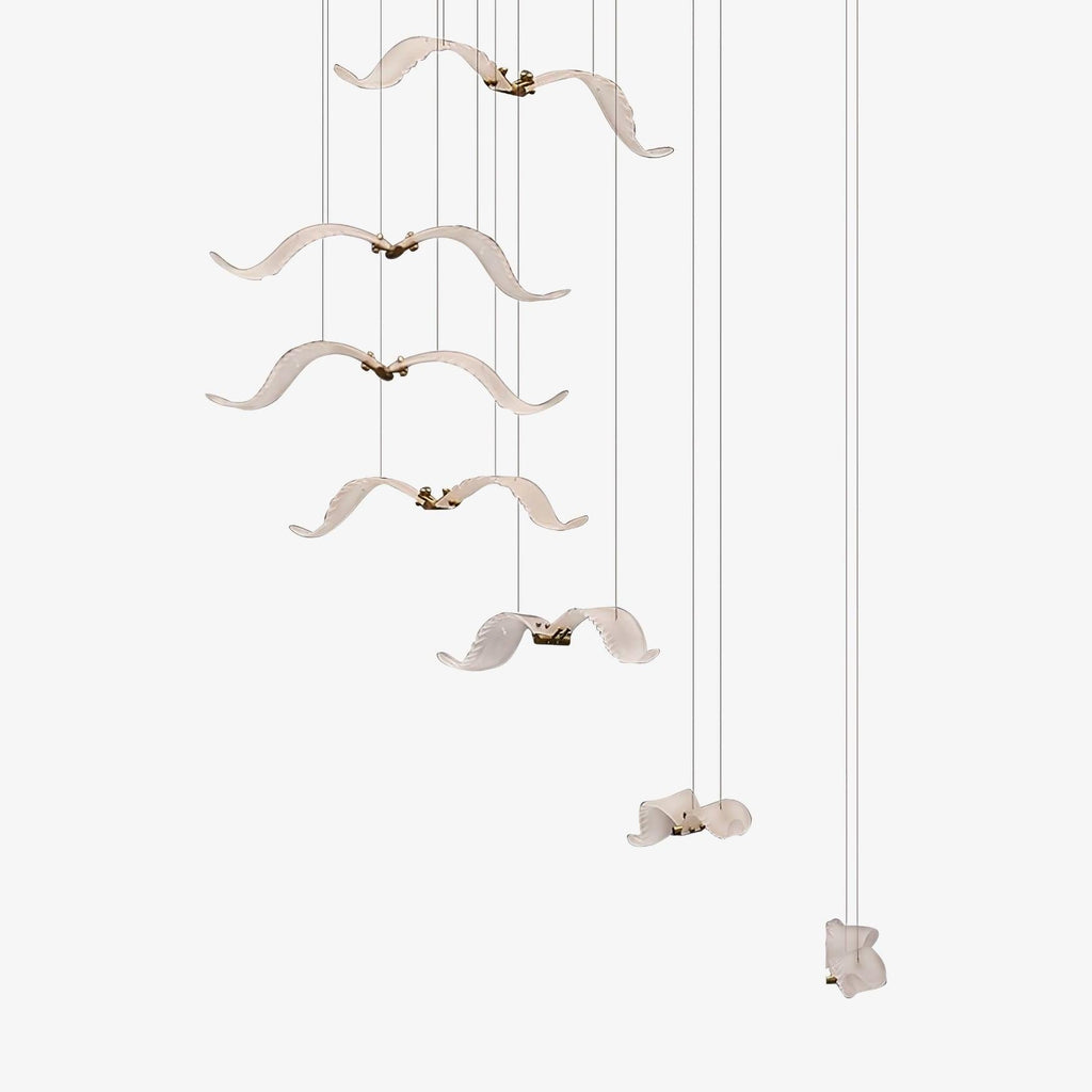 A Clérachic seagull chandelier with white glass birds hanging at different heights on fine cables, on a plain white backdrop.