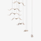 A Clérachic seagull chandelier with white glass birds hanging at different heights on fine cables, on a plain white backdrop.