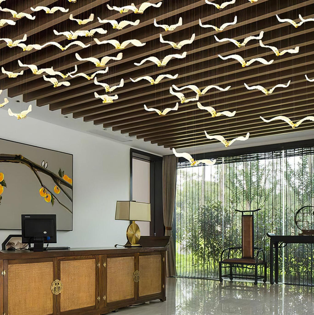 Under a dark timber slatted ceiling, this Clérachic seagull chandelier spreads a flock of gold-bodied glass gulls above a wooden sideboard.