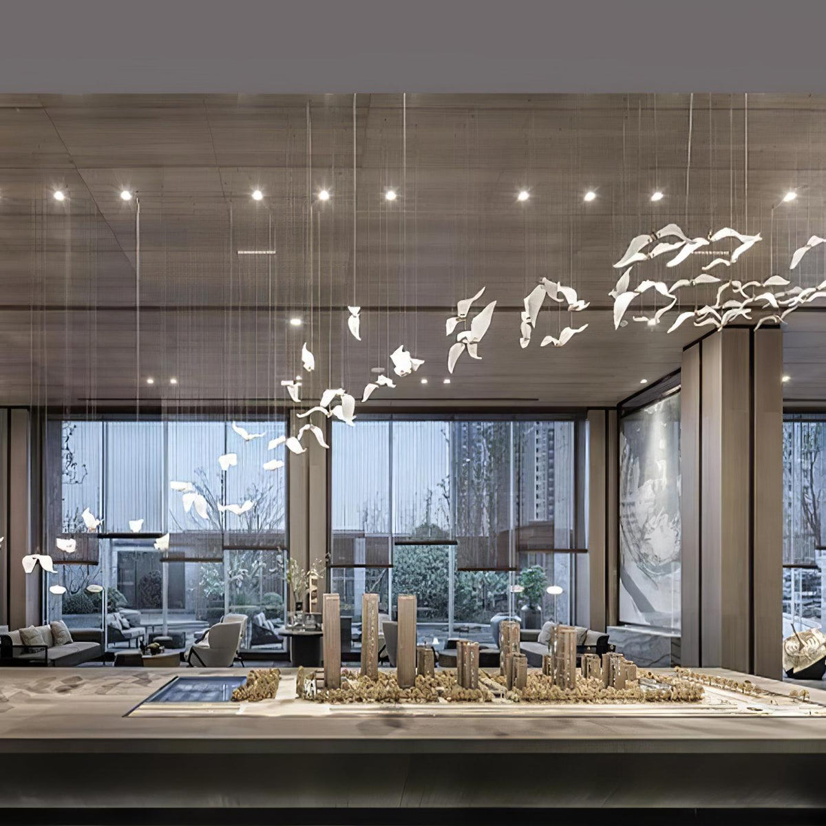 Rows of Clérachic glass gulls rise on cables above a scale model in a tall glazed hall with downlights.