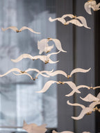Close view of Clérachic glass seagulls with outstretched wings, caught mid-flight in front of a blurred grey wall.