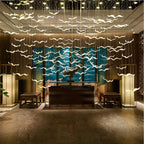 This Clérachic seagull chandelier lights an entrance hall with a warm layer of glowing glass birds above a reception table.