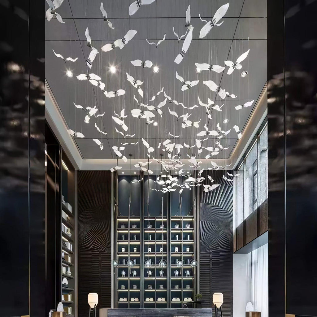 Looking up a tall dark hall, this Clérachic seagull chandelier spreads white glass gulls across the ceiling above a shelving wall.