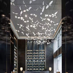Looking up a tall dark hall, this Clérachic seagull chandelier spreads white glass gulls across the ceiling above a shelving wall.