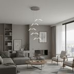 A Clérachic seagull chandelier hangs in a modern living room with a grey sofa, shelves and a view of the city.