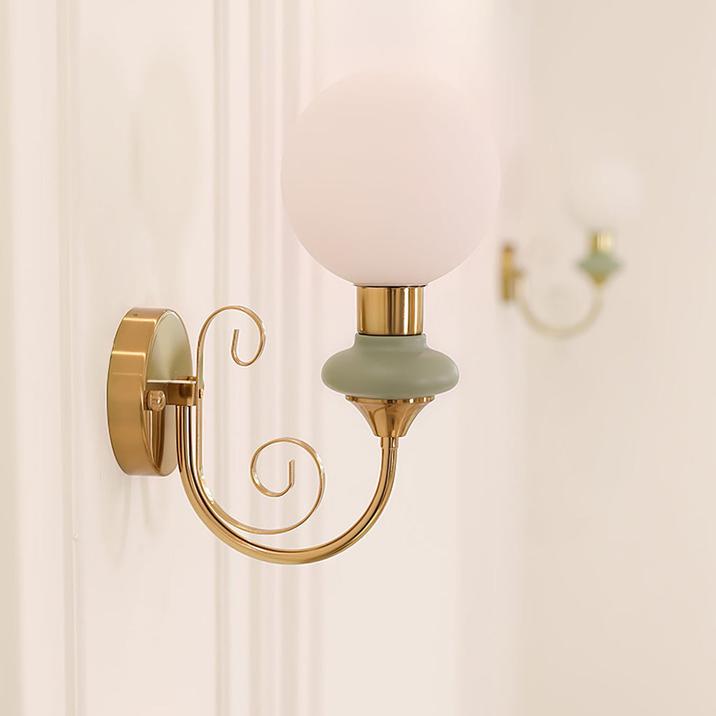 Clérachic wall sconce with a pale green collar and a softly lit globe, a second sconce blurred on the wall behind.