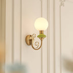 A Clérachic wall light with a green collar, its globe glowing softly against white wall panelling.
