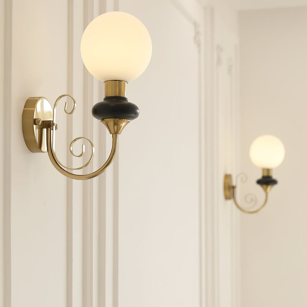 Clérachic wall light with a black collar and glowing globe on a panelled wall, with a second lit sconce further along.