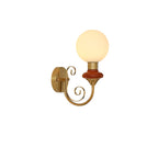 Mahogany-collared Clérachic wall light with a lit globe and gold scrolled arm, on a plain white background.
