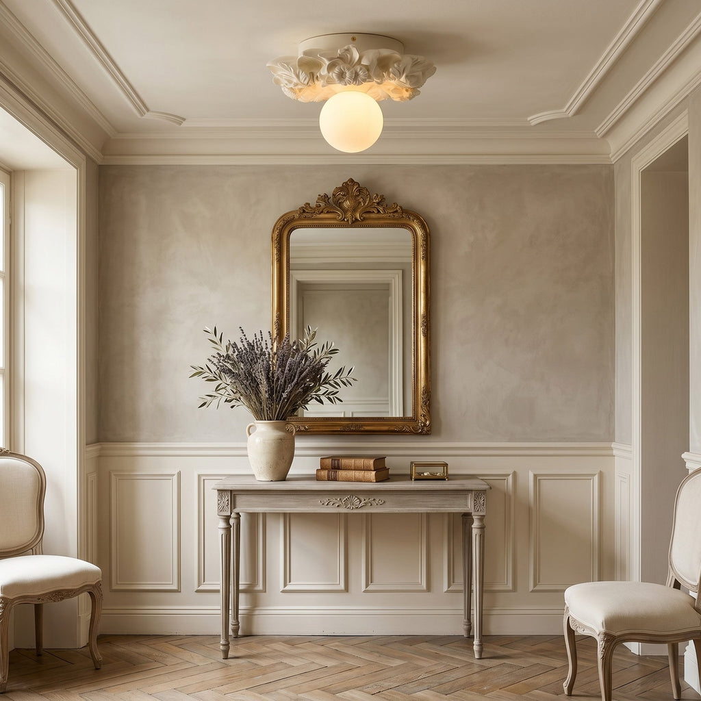 An ivory Clérachic glass sphere ceiling light above a hall console, with a gilt-framed mirror and a vase of dried lavender.