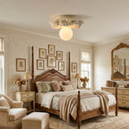 Ivory Clérachic ceiling light above a four-poster bedroom with patterned wallpaper, two bedside lamps and a gilt mirror.