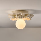 Ivory Clérachic ceiling light on a grey ceiling, its carved flower collar and frosted sphere glowing softly.