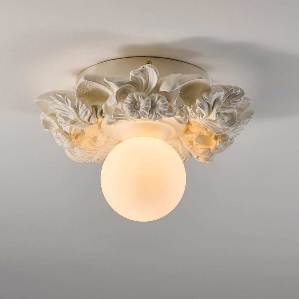 Angled view of this Clérachic light in ivory white, showing the layered resin flowers and leaves around the glass sphere.