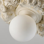 Close view of the frosted glass sphere and ivory resin petals on this Clérachic ceiling light.