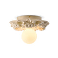 Ivory white Clérachic flush-mount light with a glowing glass sphere under its resin flower collar, on a white background.