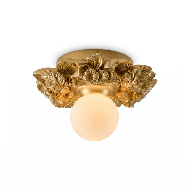 Gilded gold Clérachic flush-mount light with a glowing glass sphere under its resin flower collar, on a white background.