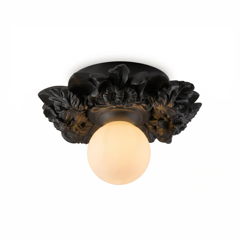 Matte black Clérachic flush-mount light with a glowing glass sphere under its resin flower collar, on a white background.