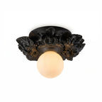 Matte black Clérachic flush-mount light with a glowing glass sphere under its resin flower collar, on a white background.