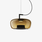 Wide amber glass Clérachic pendant with a black bracket and cord, a small light visible inside, on a plain white backdrop.