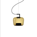Squat amber glass Clérachic pendant with a black base and a thin cord, shown lit on a plain white backdrop.