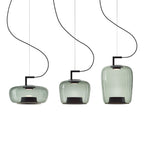 Three grey-green glass Clérachic pendants in wide, squat and tall shapes hang at different heights on a white backdrop.