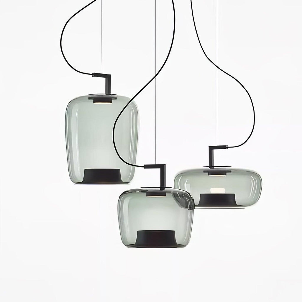 Three pale grey-green glass Clérachic pendants in tall, squat and wide shapes cluster on a white backdrop.