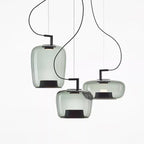 Three pale grey-green glass Clérachic pendants in tall, squat and wide shapes cluster on a white backdrop.