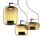 Three amber glass Clérachic pendants in tall, squat and wide shapes, shown close and lit on a white backdrop.