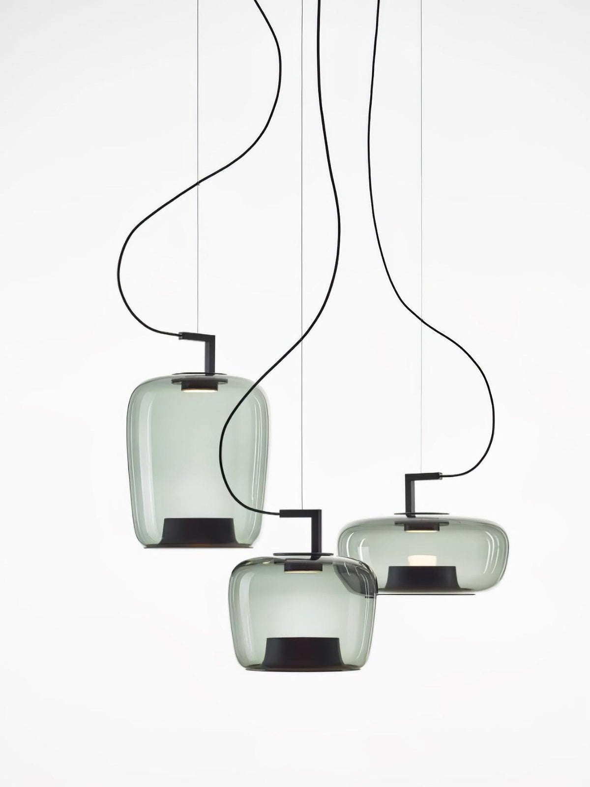 Three small grey-green glass Clérachic pendants hang at staggered heights on thin cords against a white backdrop.