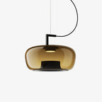 Wide amber glass Clérachic pendant with a black bracket and a small lit centre, on a plain white backdrop.