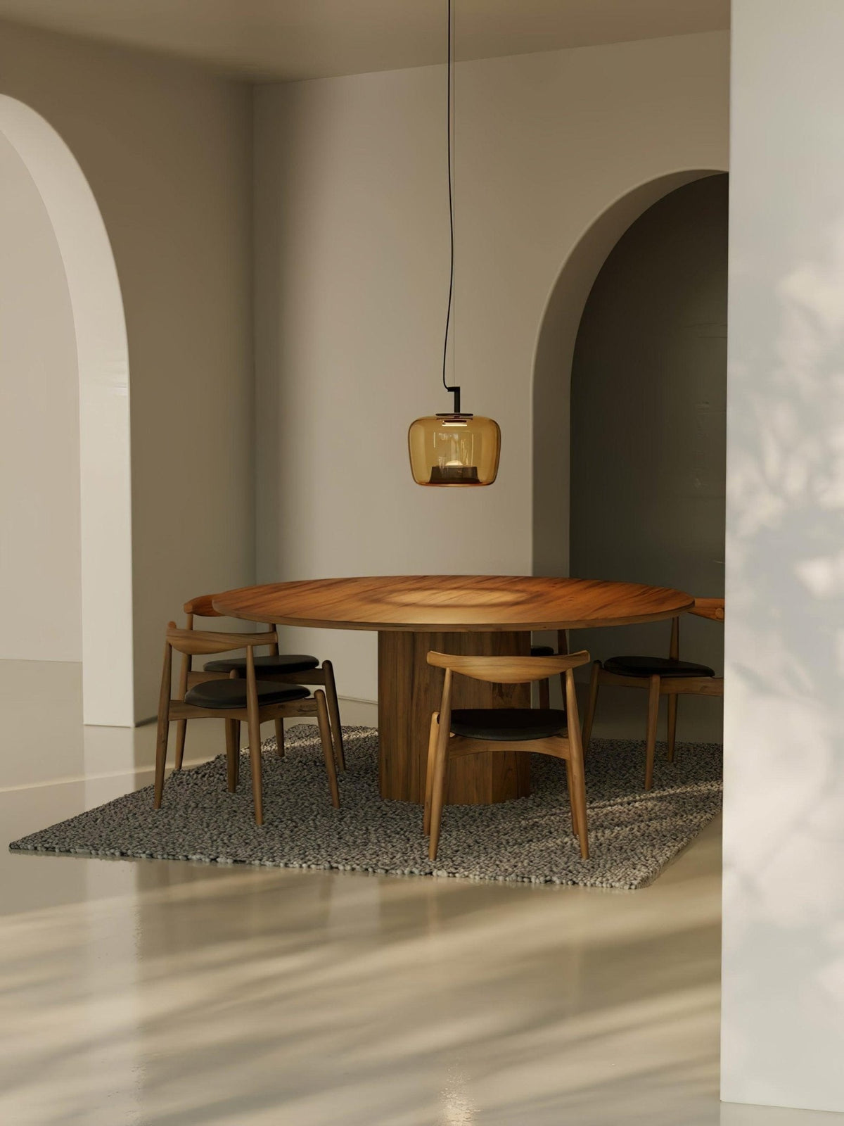 Distant view of an amber Clérachic pendant above a round wooden table in an arched room with a patterned rug.